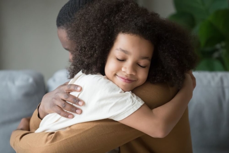 Man hugging daughter with a smile on her face.